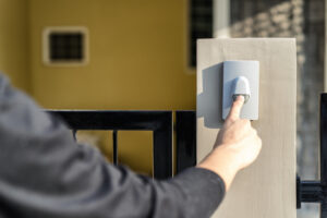 Man's hand pressing a doorbell button with sunlight.